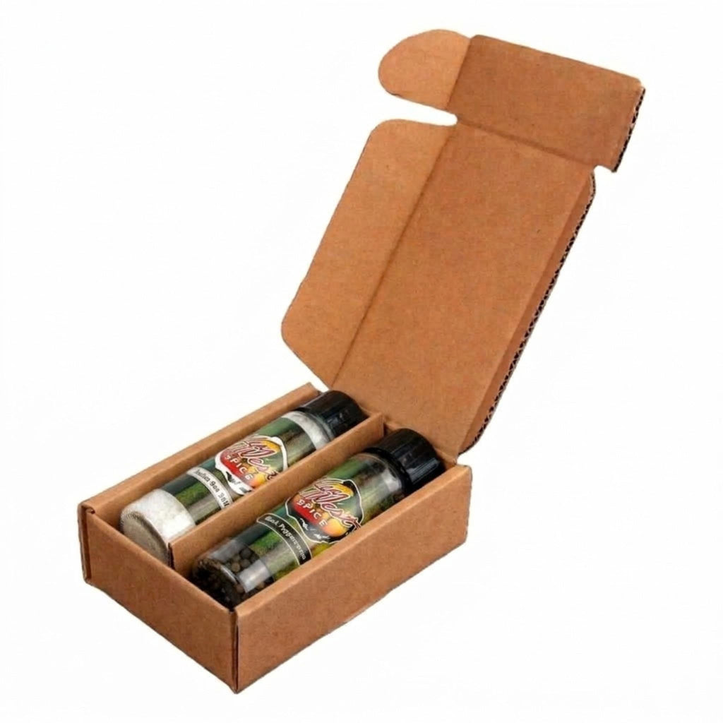 An open brown cardboard box containing two spice or herb seasoning bottles with black caps and colorful labels, photographed on a plain white background.
