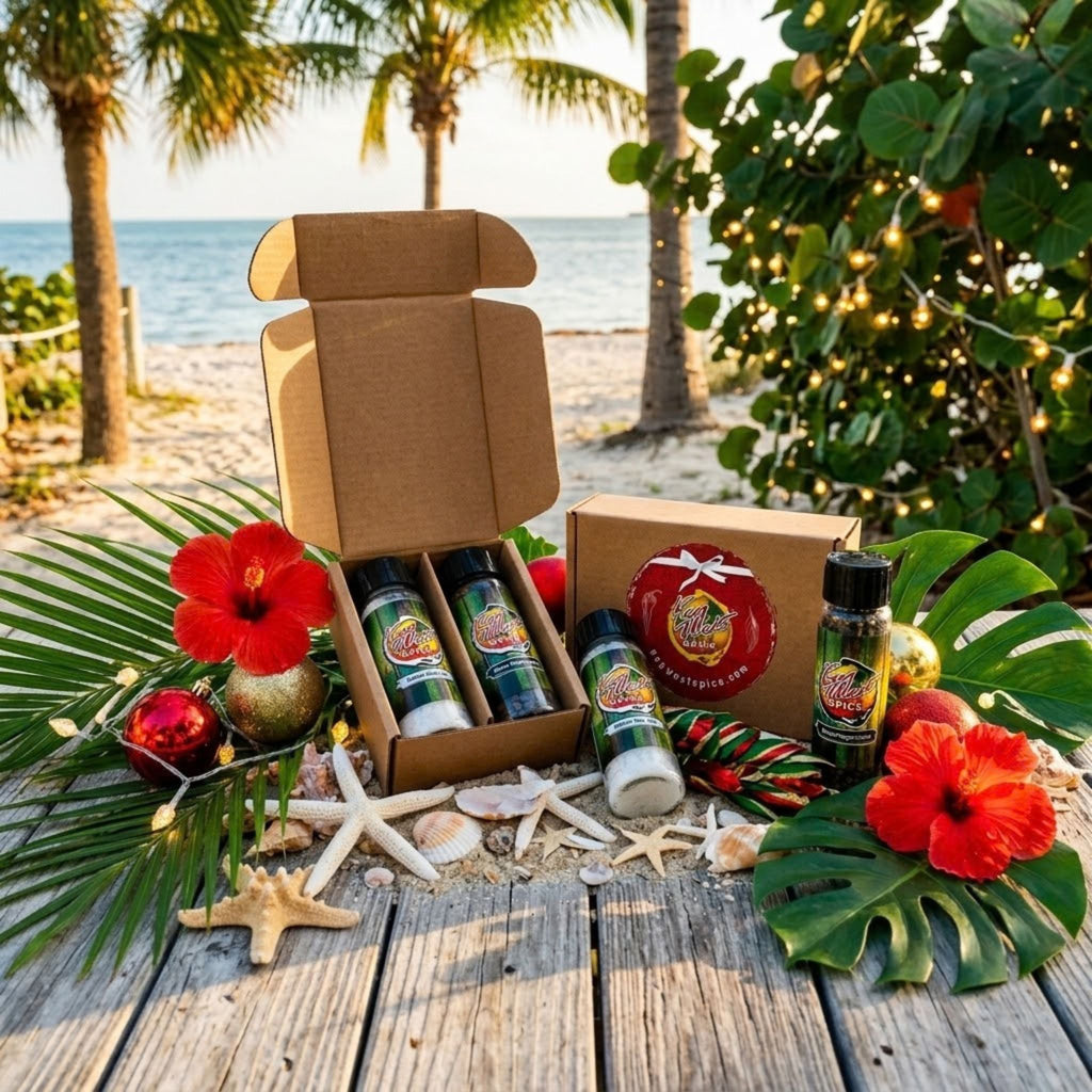 A tropical beach-themed gift set displayed on a wooden table with palm trees, ocean, and string lights in the background. The set includes an open brown cardboard box with three green-labeled bottles, a round red-labeled gift tin, and a single small bottle, surrounded by red hibiscus flowers, green leaves, starfish, and seashells.