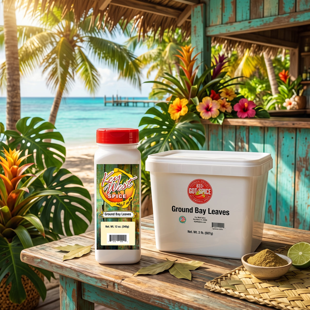 Two containers of Red Dot Spice Ground Bay Leaves displayed on a rustic wooden table in a tropical beach setting with palm trees and turquoise water.