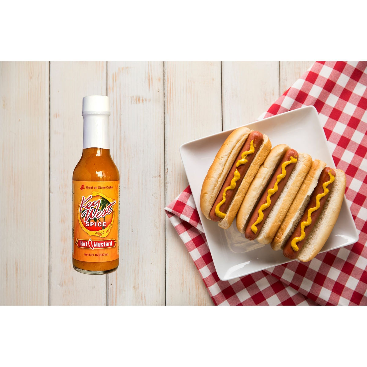 Key West Spice hot mustard in a 5 oz jar, served with hot dogs, showcasing its spicy, vibrant yellow appearance and creamy texture.