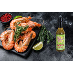 Key West Spice Key Lime Fusion Hot Sauce bottle next to cooked shrimp garnished with lime slices, showcasing flavor and vibrant color.